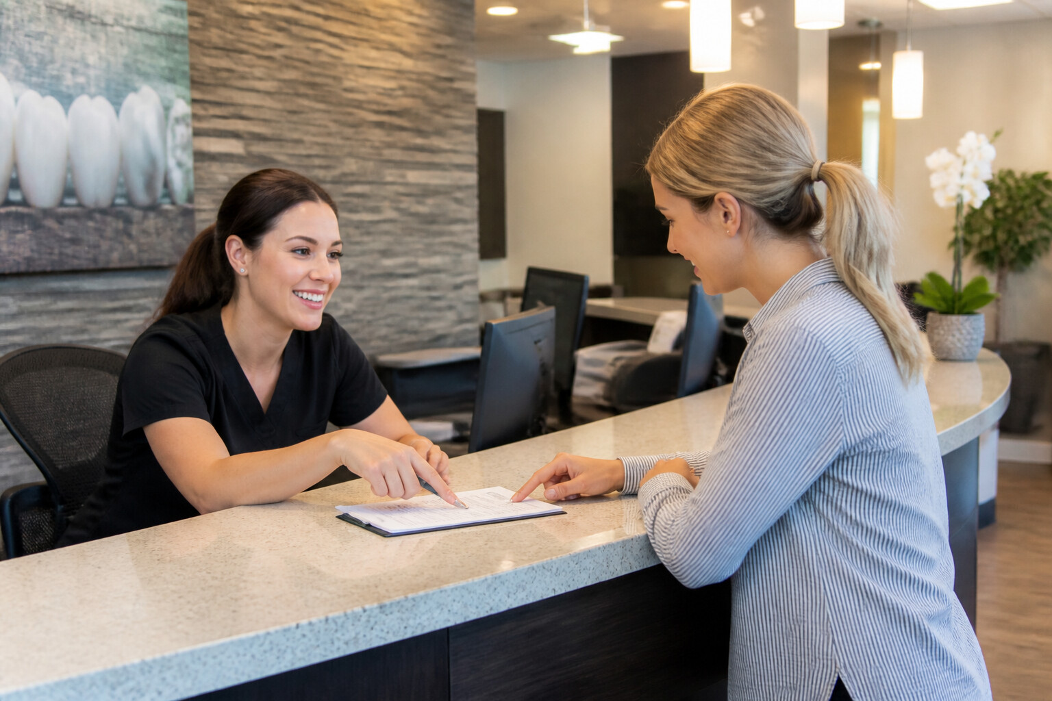 Dental office receptionist helping a patient with insurance paperwork at South Tulsa Dental